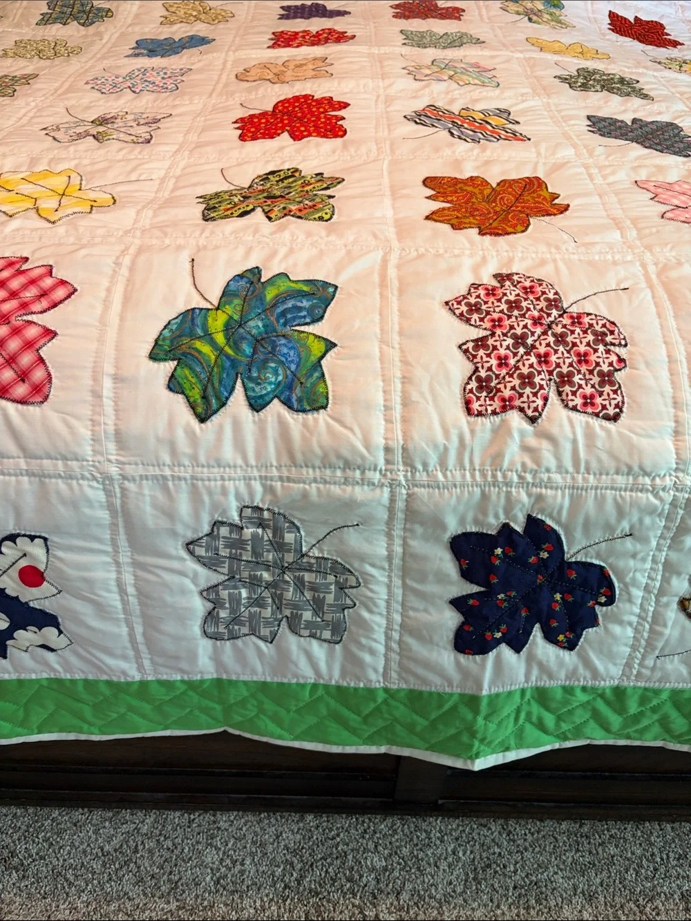 Vintage quilt handcrafted with color leaf blocks on white with green trim